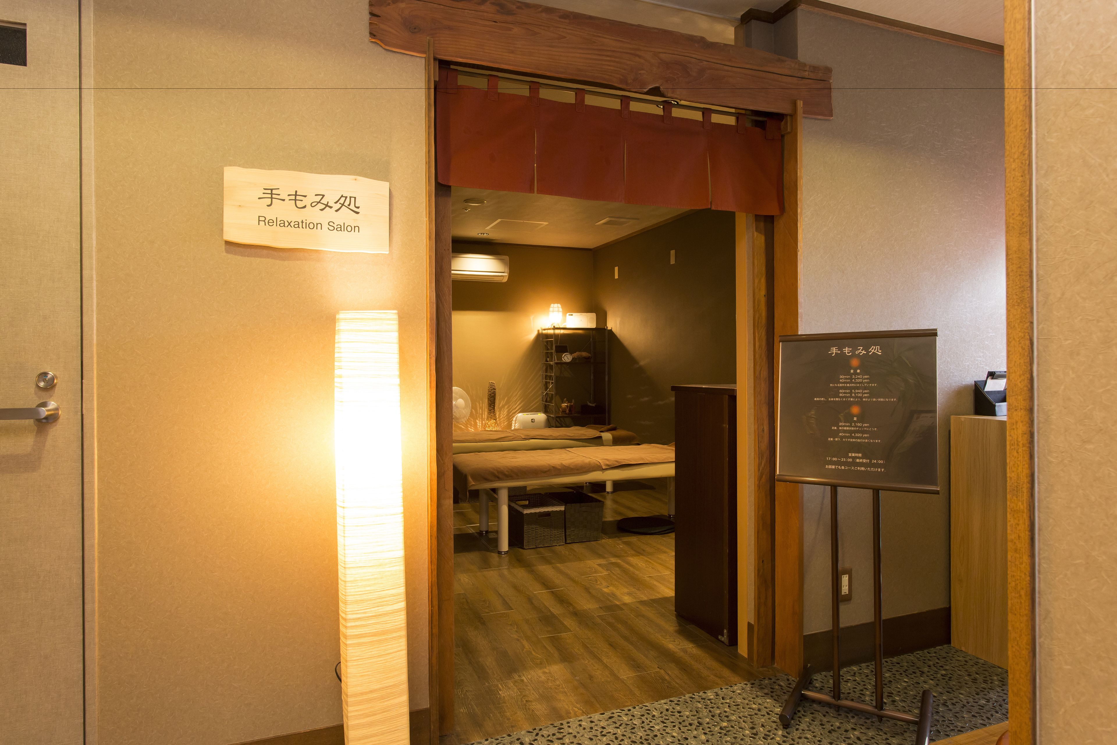 A room with a bed, a desk, and a chair. There is a sign on the wall that reads "Relaxation Salon".