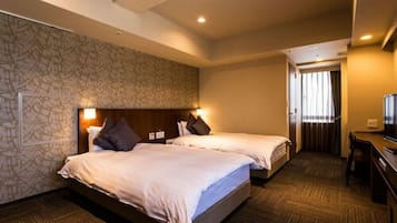 A hotel room with two beds, a desk, and a television.