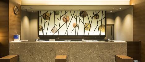Un baño moderno con encimera de mármol, dos lavamanos, un espejo grande con un revestimiento decorativo y bancos de madera.
