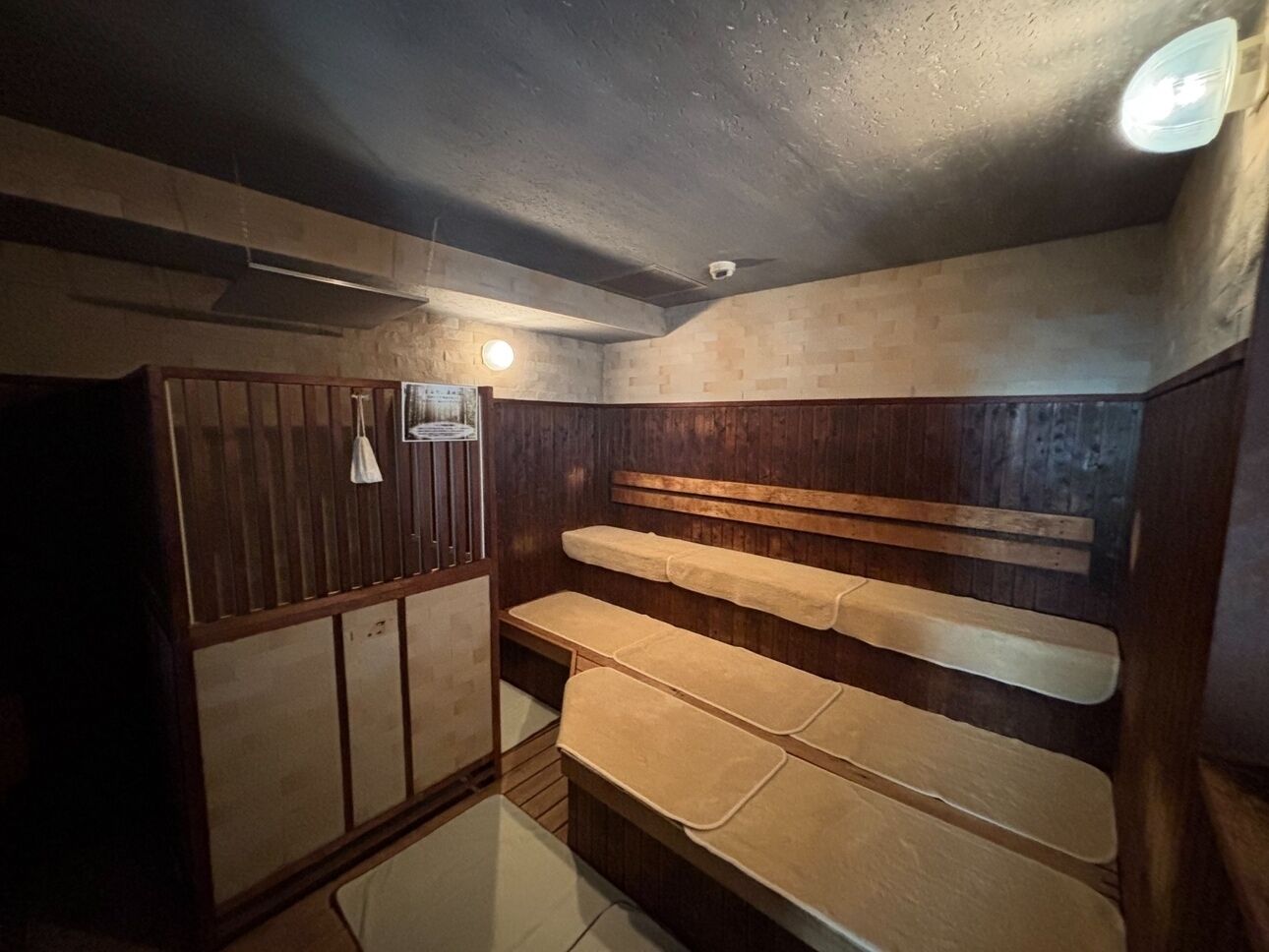 Een kleine, zwak verlichte kamer met houten wanden en bankjes.