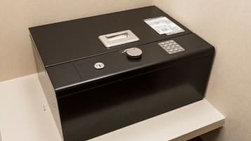 A black safe deposit box with a key slot, a lock, and a warning label.