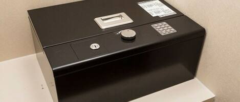 A black safe deposit box with a key slot, a lock, and a warning label.