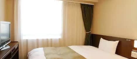 A hotel room with a bed, a TV on a stand, a window with curtains, and a nightstand with a lamp.