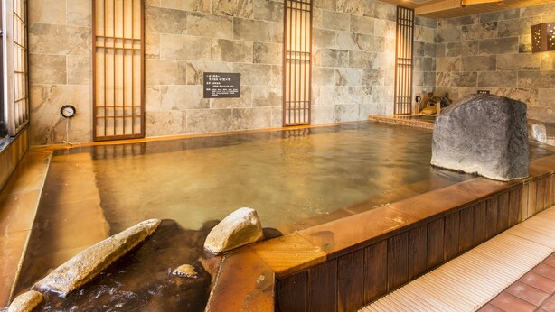 Un baño de aguas termales con paredes de piedra y detalles de madera.