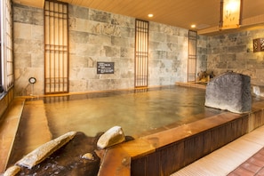 A hot spring bath with stone walls and wooden accents.