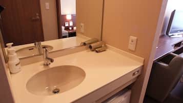 A hotel bathroom with a sink, mirror, and toiletries.