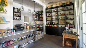 Una panadería con estantes llenos de productos horneados, una estación de café y una variedad de plantas y adornos.