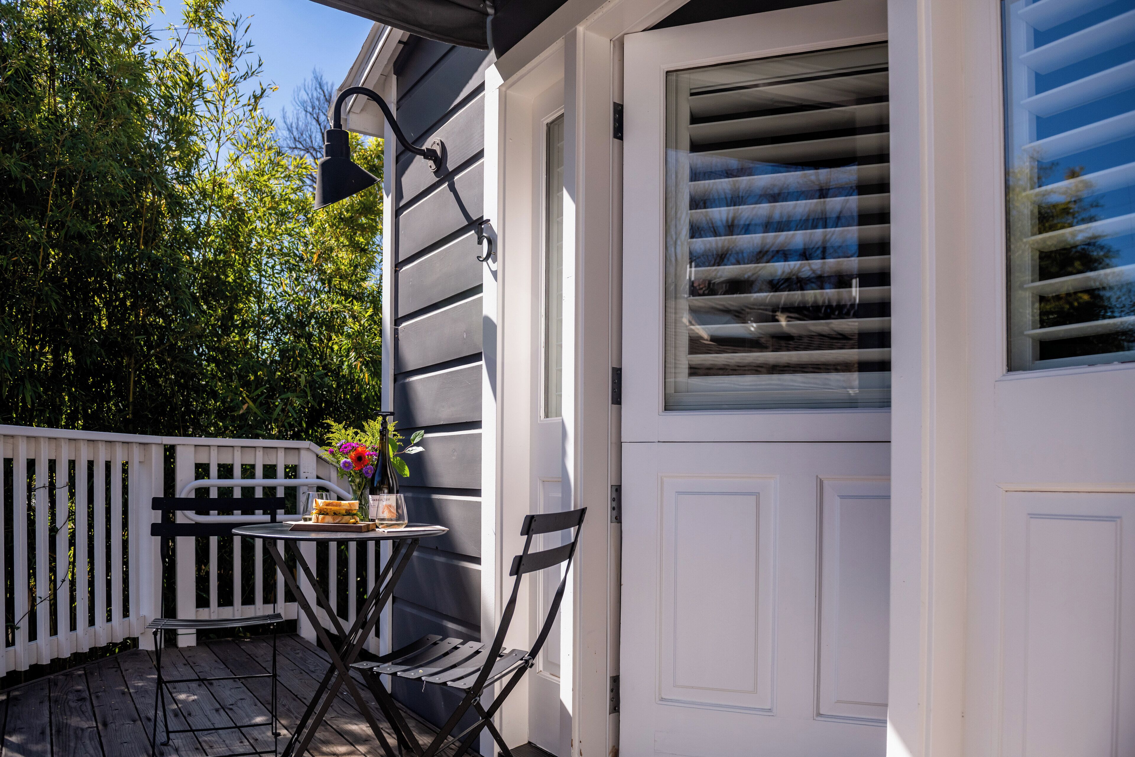 A patio with a table and chairs, a potted plant, and a white door.