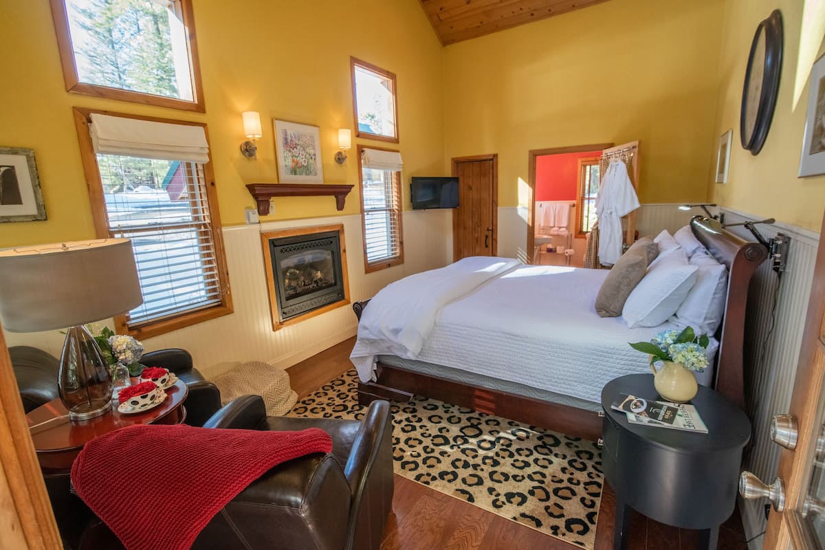 A cozy bedroom with a bed, a television, a fireplace, and a leopard print rug.