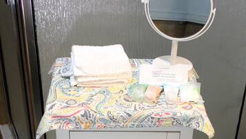 A bathroom vanity with a patterned tablecloth, a folded towel, a makeup remover wipe, and two rolls of Scott toilet paper.