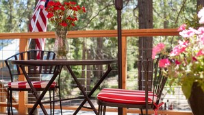 A patio with a table and chairs, an American flag, and a vase with red flowers.