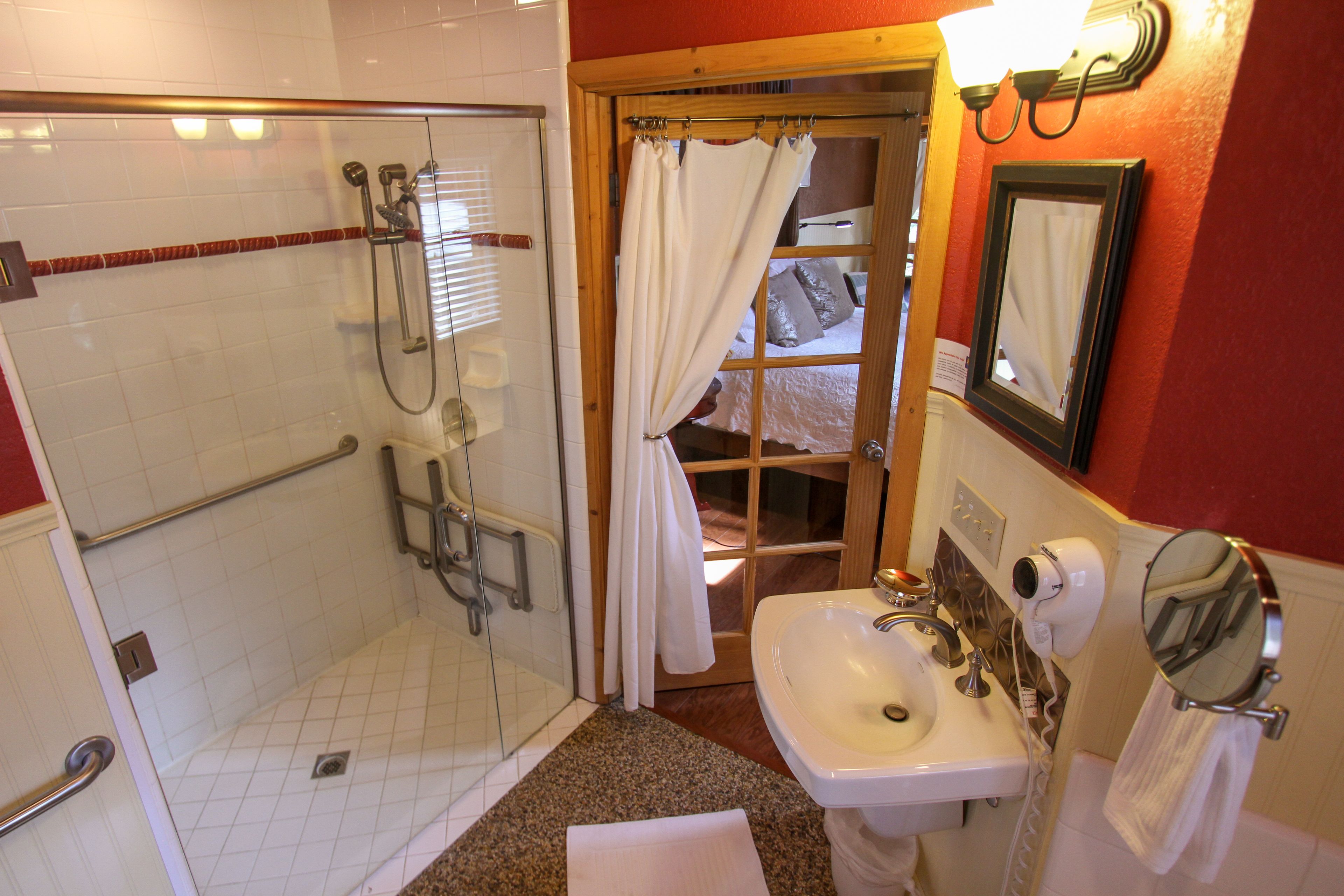 Ein Badezimmer mit Duschkabine, Waschbecken, Spiegel und Handtuchhalter.