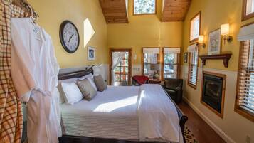 A bedroom with a bed, a clock, a fireplace, and a window with blinds.