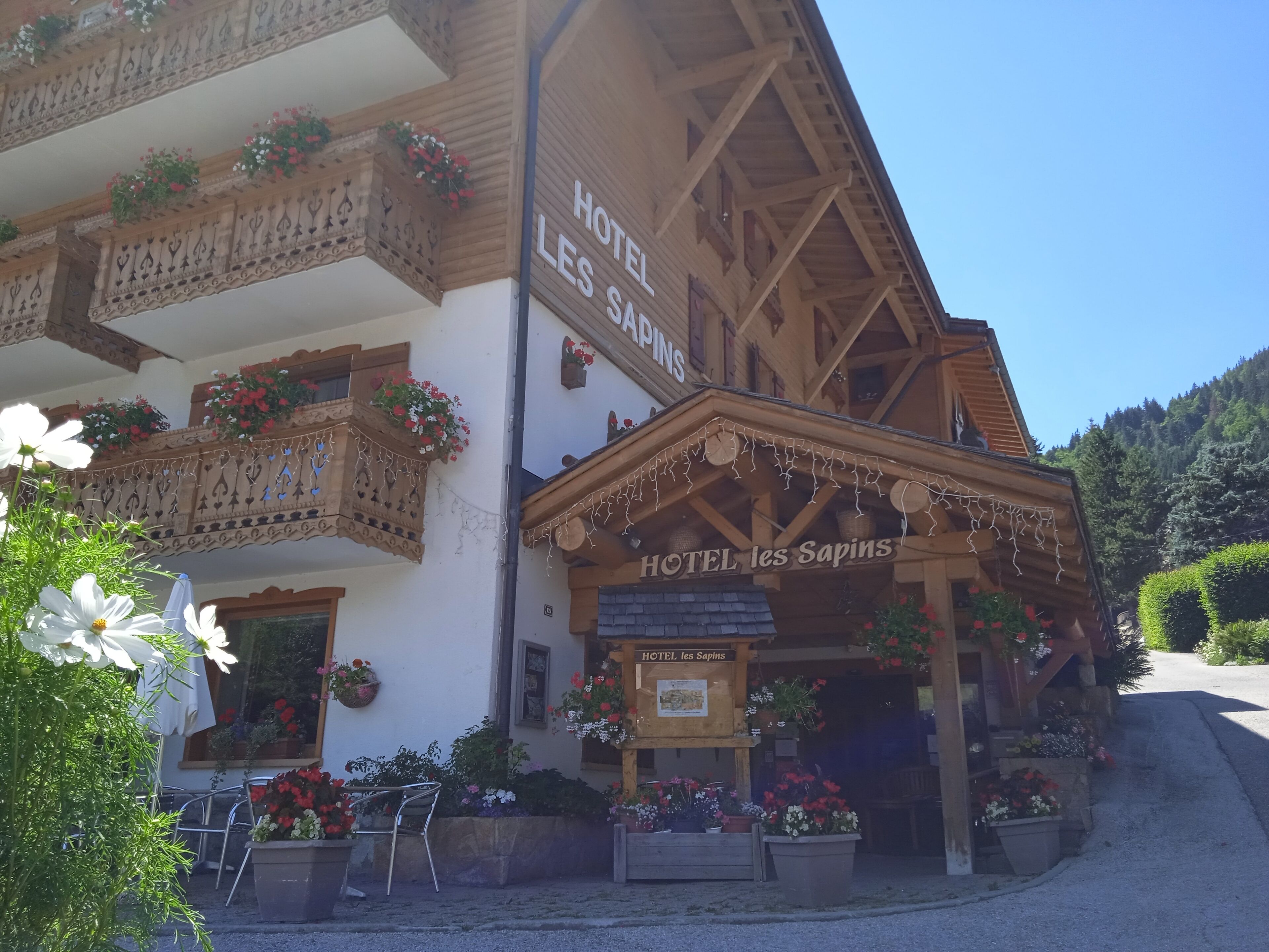 Un edificio de madera tradicional con balcones decorados con flores, con el letrero 