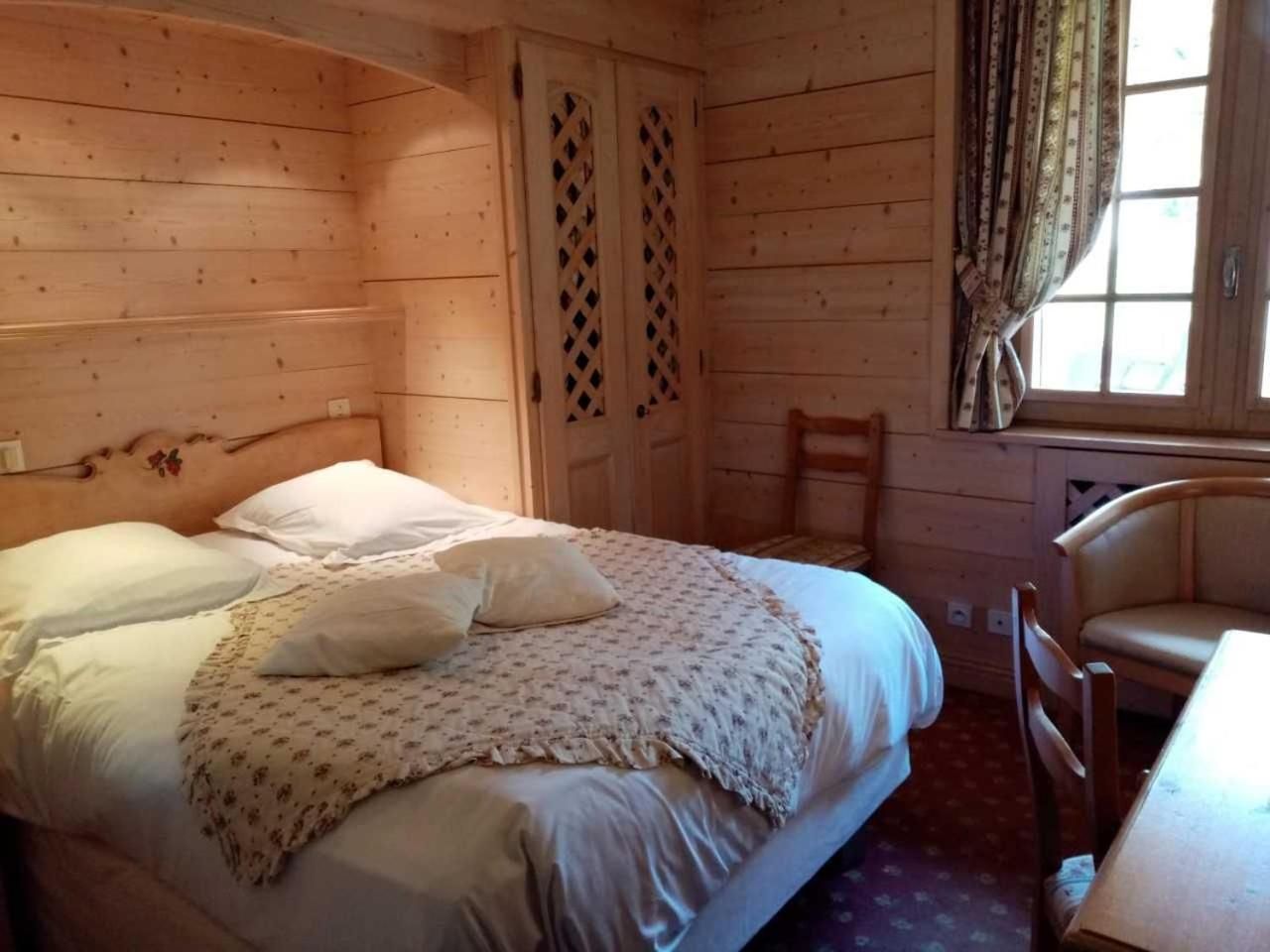 Ein Zimmer mit Holzboden, einem Bett, einem Stuhl und einem Fenster.