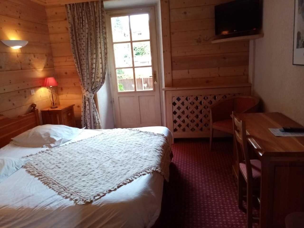Una habitación acogedora con una cama, un escritorio y un televisor.