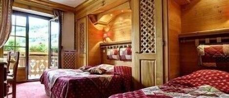 A room with two beds, a wooden ceiling, and a view through a window.