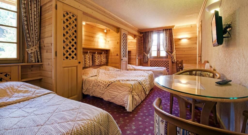 Een gezellige kamer met twee bedden, een ronde glazen tafel en een houten hoofdbord.