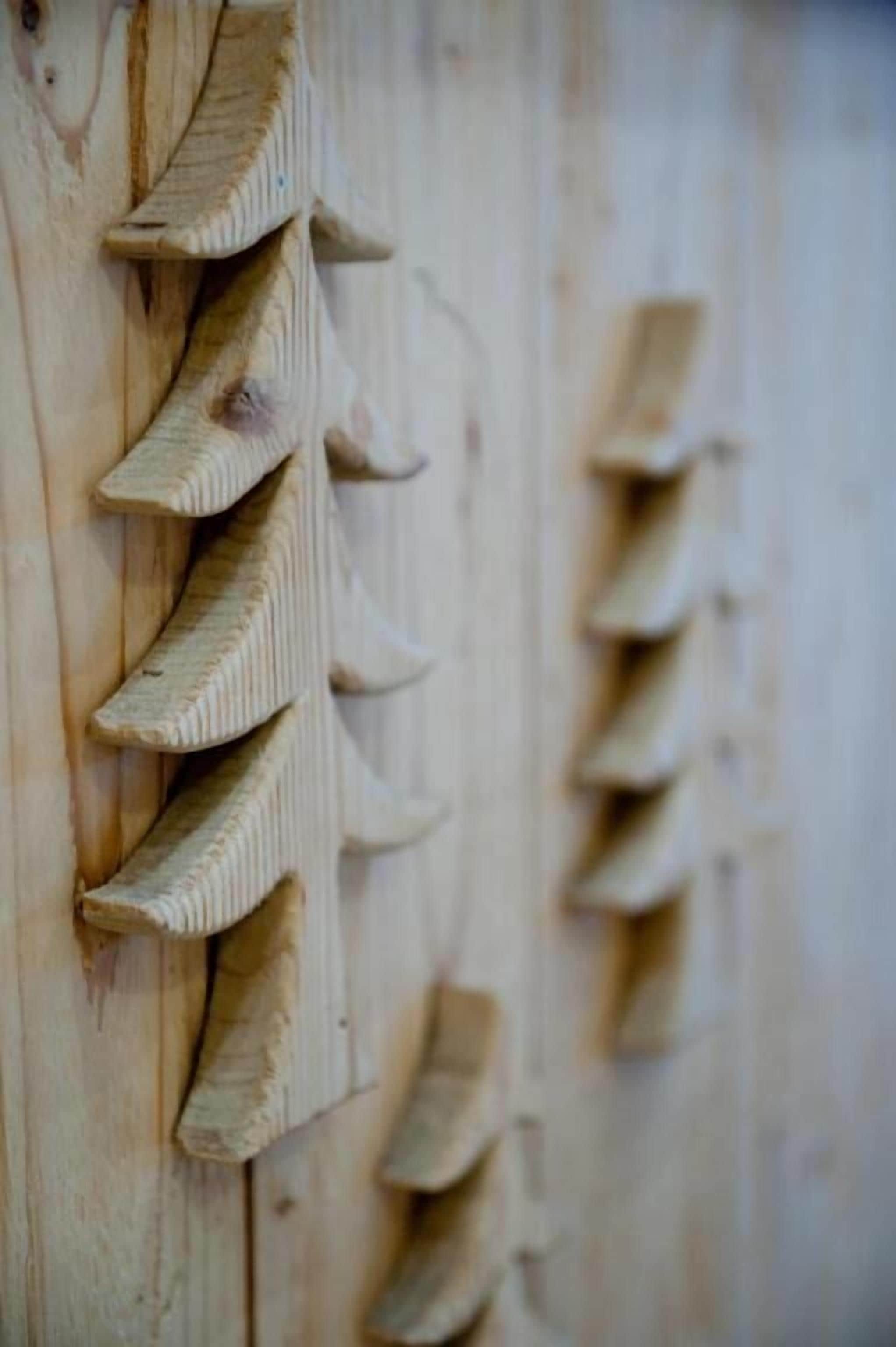 Una pared de madera con una serie de formas talladas que recuerdan a hojas.
