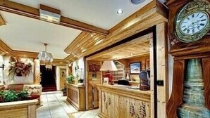 Un interior de madera con una recepción, un área de estar y una escalera.