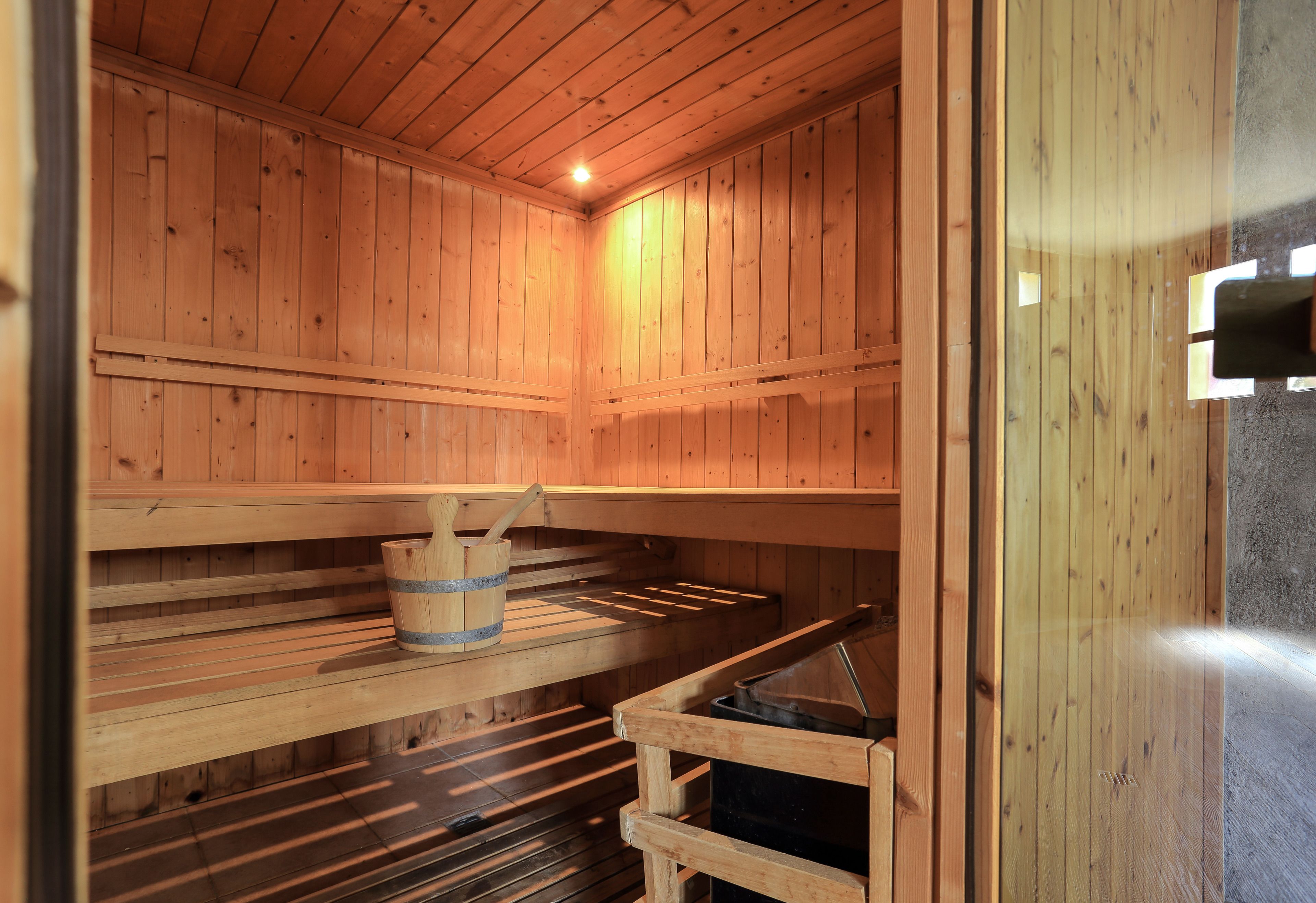 Una sauna con paredes y bancos de madera, un balde y un generador de vapor.