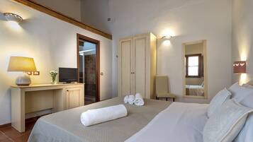 A neatly arranged hotel room with a bed, a desk with a lamp, a television, and a wardrobe.