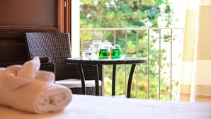 Un balcón con mobiliario de mimbre, una mesa con juego de té y una toalla enrollada.