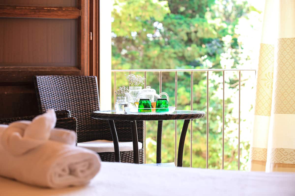 A balcony with wicker furniture, a table with a tea set, and a rolled towel.