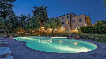Relax by the oval-shaped pool surrounded by lounge chairs and lush greenery.