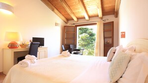 Habitación de hotel con una cama grande, un escritorio con computadora, una silla y vistas al exterior.