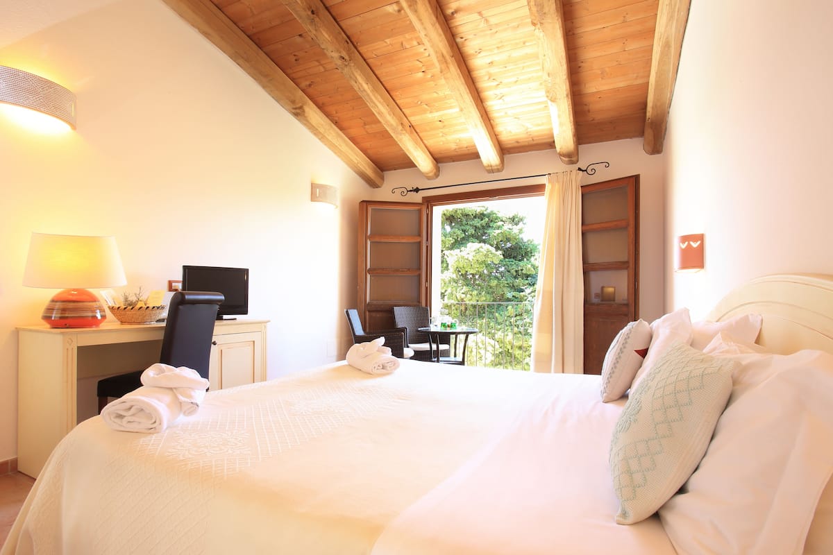 A hotel room with a large bed, a desk with a computer, a chair, and a view of the outdoors.