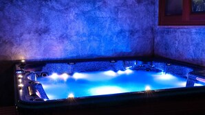 Un jacuzzi iluminado con luz azul, rodeado por un muro con textura.