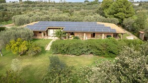 A house with a solar panel roof, surrounded by lush greenery and trees. - Su Leunaxiu (Soleminis)