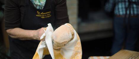 A person handling a loaf of bread, possibly in a bakery or kitchen setting.