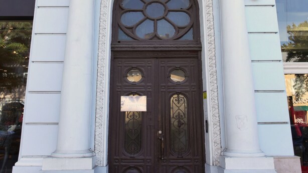 Fachada de edificio con una amplia entrada en arco, un letrero que dice "EKATERINA" y detalles arquitectónicos clásicos.