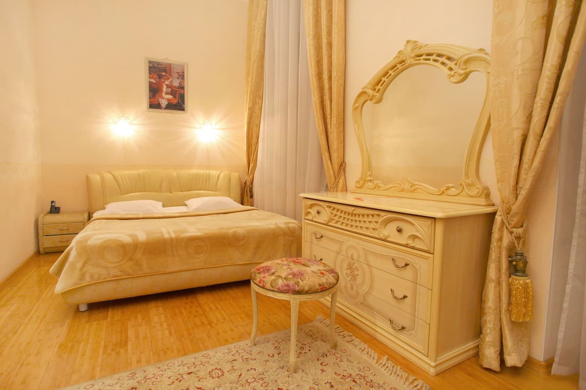 A bedroom with a bed, a dresser, a mirror, and a nightstand.