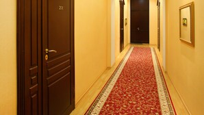 Un pasillo con alfombra roja, puertas de madera y un cuadro enmarcado en la pared.