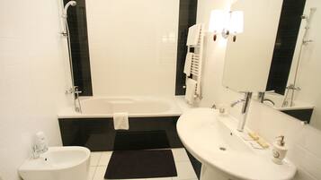A modern bathroom with a bathtub, a sink, a bidet, and a mirror.