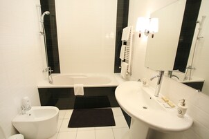 Un baño moderno con bañera, lavamanos, bidé y espejo.