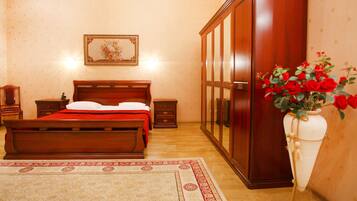 Un dormitorio con una cama de madera, una mesita de noche, un aparador y un jarrón de rosas rojas.