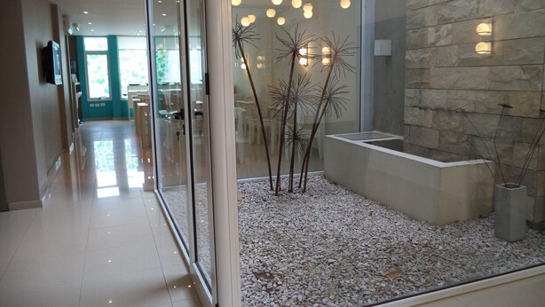 A modern interior with a glass partition, a pebble-filled area, and a stone wall. - Apart Via 51 (La Plata)