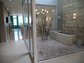 Een modern interieur met een glazen scheidingswand, een gebied gevuld met kiezelstenen en een stenen muur.