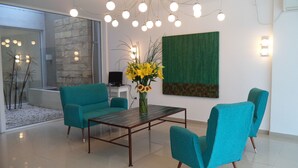 A modern living room with teal chairs, a wooden coffee table, and a green textured wall. - Apart Via 51 (La Plata)