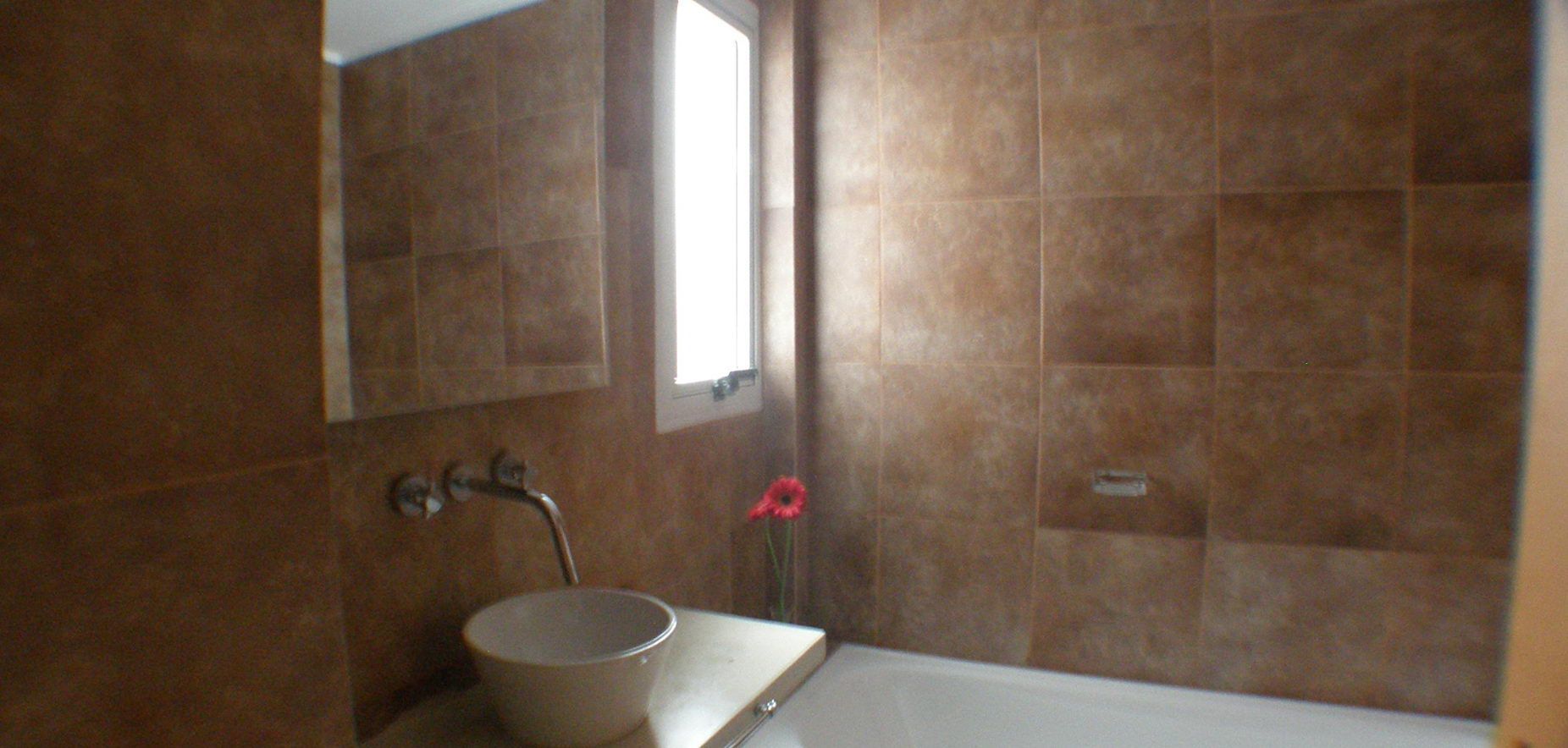 A bathroom with a sink, mirror, and a window.