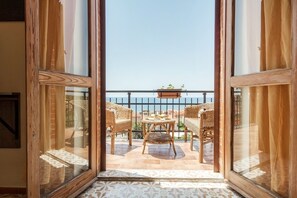 A balcony with wicker furniture and a view of the sea.