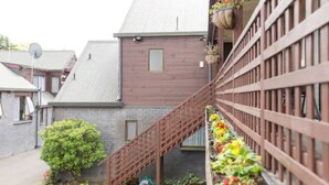A residential building with a wooden staircase, a brick wall, and a window. - Strathern Motor Lodge (Christchurch)