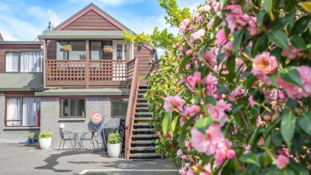 A two-story building with a balcony, outdoor seating, and potted plants. - Strathern Motor Lodge (Christchurch)