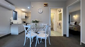A compact living space with a dining area, kitchenette, and a bedroom. - Strathern Motor Lodge (Christchurch)