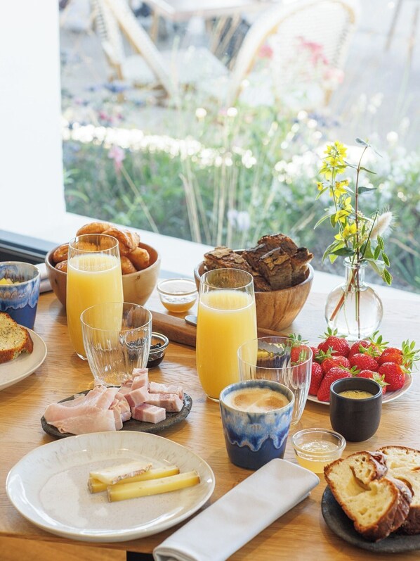 Une table de petit-déjeuner avec des croissants, des fraises et des verres de jus de fruits.