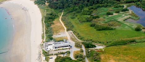 Vista aérea de una zona costera con playa, campo de golf y un edificio grande con varios espacios de estacionamiento.